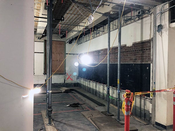 a room under construction with a blackboard below bricks, there is an x on one wall