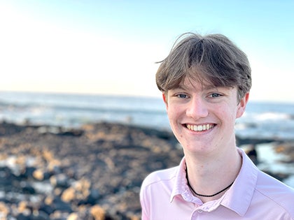 Luke Folsom smiles for a photo while at a beach