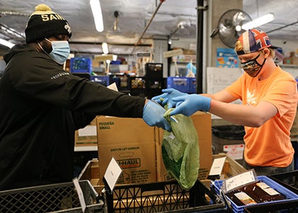 Two people work together in a warehouse to pack food