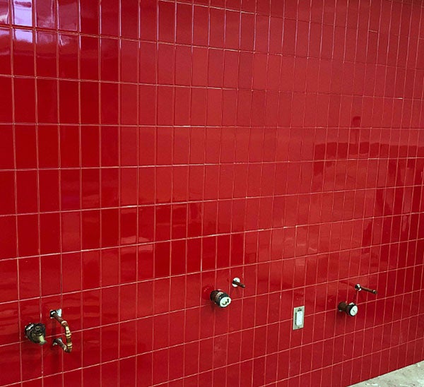 a red tiled wall with pipes