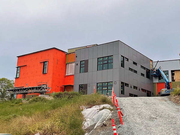 a 2 story building on a hill -- half gray, half orange