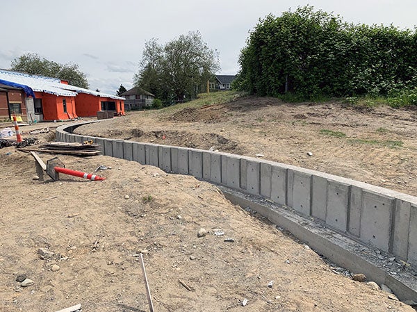 a curved concrete wall with soil on each side