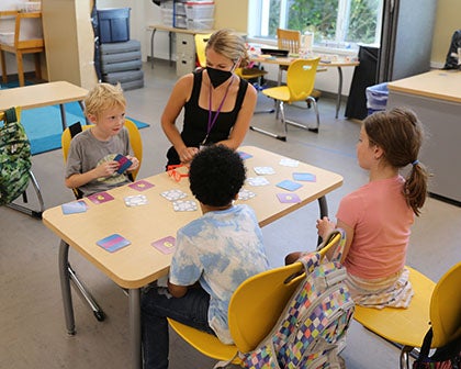 A small group of students sit together with a teacher in a classroom