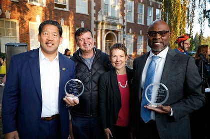Four people stand together with awards