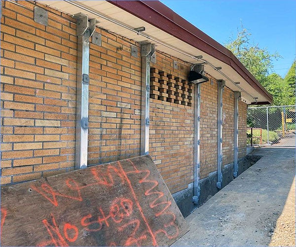 a brick building has steel beams installed vertically on it