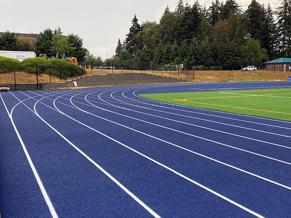 a blue running track with a green field next to it