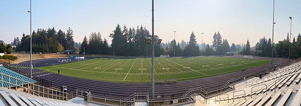 a panoramic view of a field and track from stadium bleachers