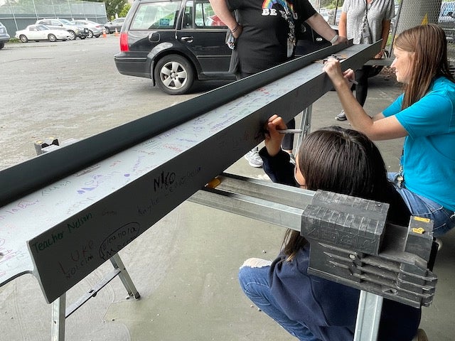 adult and child signing a steel beam outside