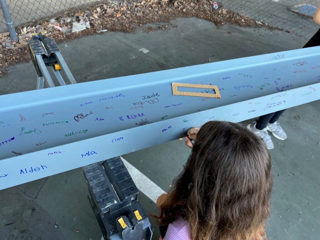 a child writes on a white steel beam