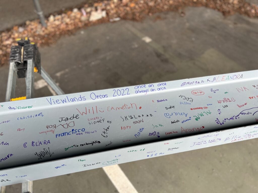 a white steel i-beam has signatures in various colors on it