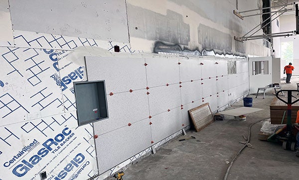 Large wall tiles being installed on tile backer board on the wall