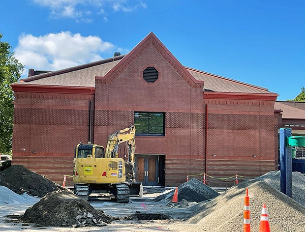 a 2-story brick building with a construction digger