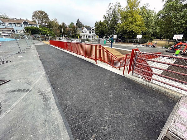 an asphalt area with a fence and stairs