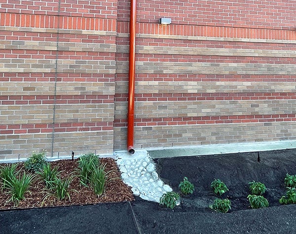 a downspout on a brick building with a drainage area below