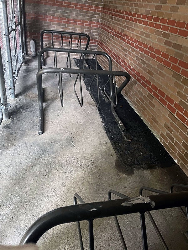 bike racks inside a fence by a brick building