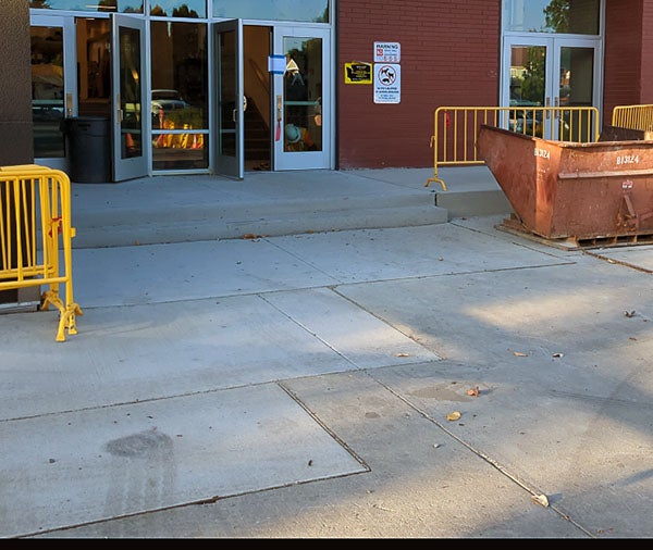 a concrete walkway leads to glass doors