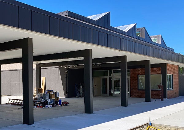 a walkway with metal beam arches leads to a door