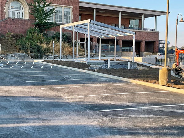 an asphalt parking lot with framing next to it for a shelter