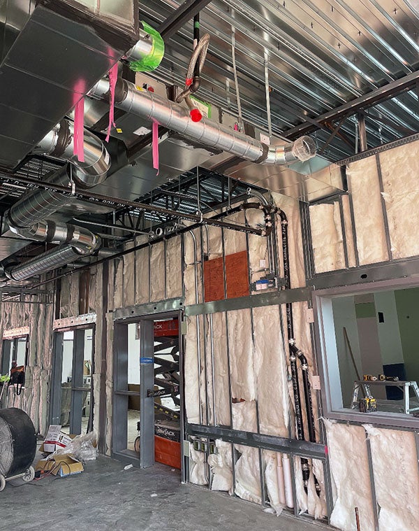 an unfinished wall with insulation between metal studs