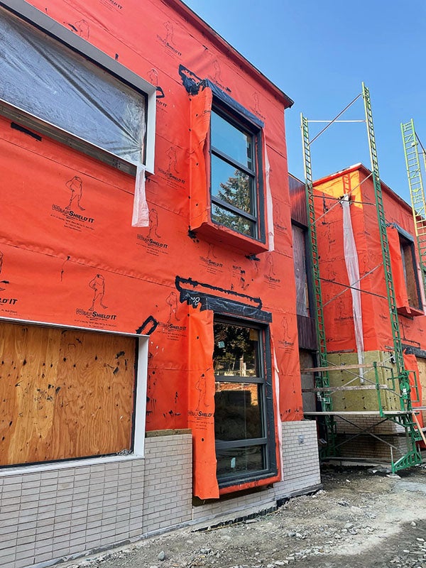 a close view of part of a two-story building with waterproof wrap and some windows in place