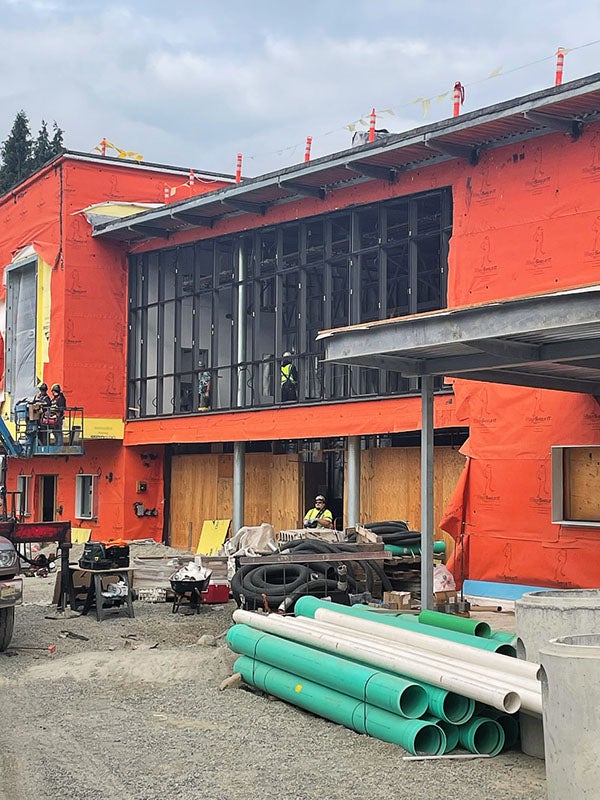 exterior of a building under construction with large window spaces and workers