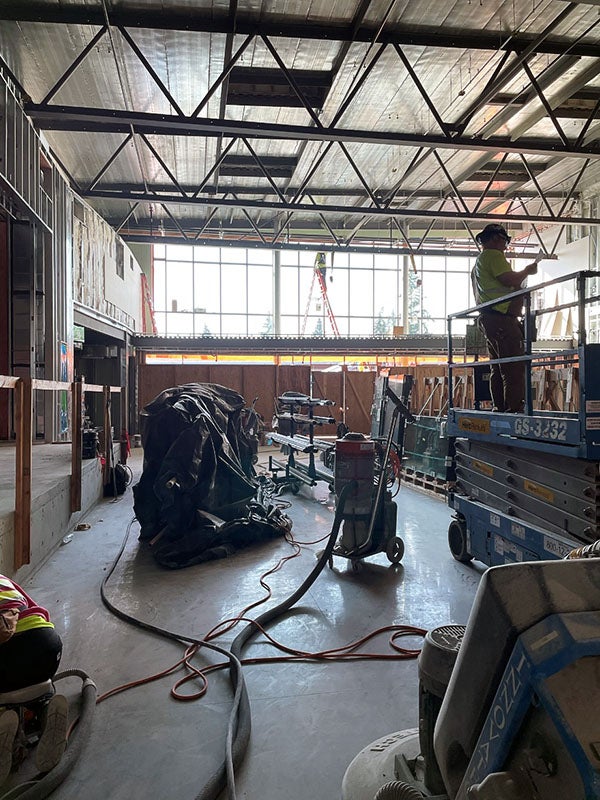 a large room under construction with tall windows at one end
