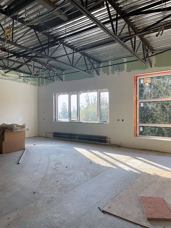 a room under construction with a ceiling grid below a metal ceiling