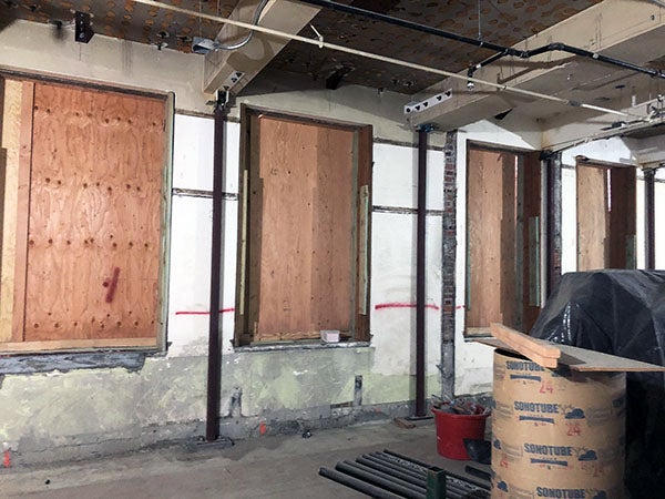 a large room under construction with plywood over the window openings