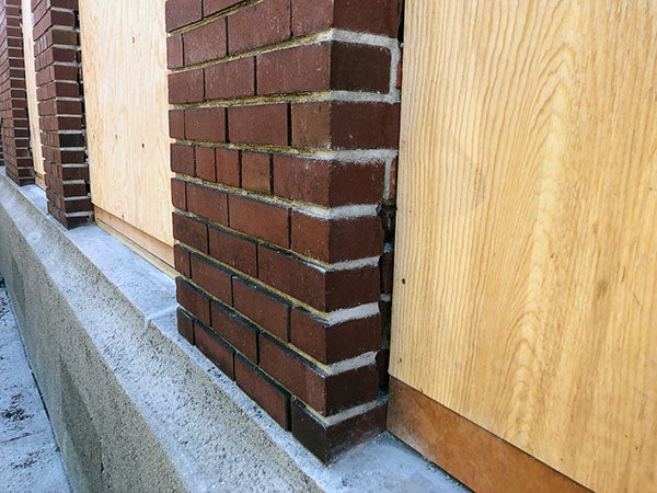 a close view of a brick section of wall with plywood window next to it