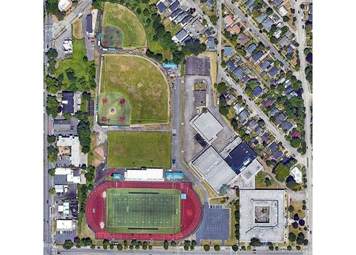aeriel photo of a large building with playfields surrounded by houses