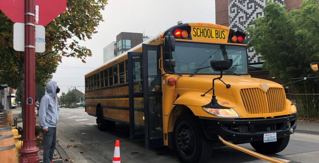 A parent watches at their student boards the school bus.