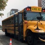 A parent watches as their student boards the school bus.