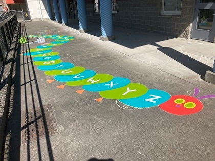 A painted caterpillar on a school sidewalk in the playground