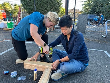 Two volunteers work together on a project in a school courtyard