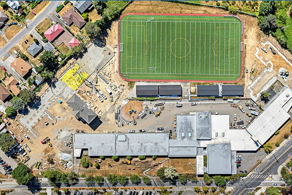 aerial view of a large field with a building on one side and construction underway next to it
