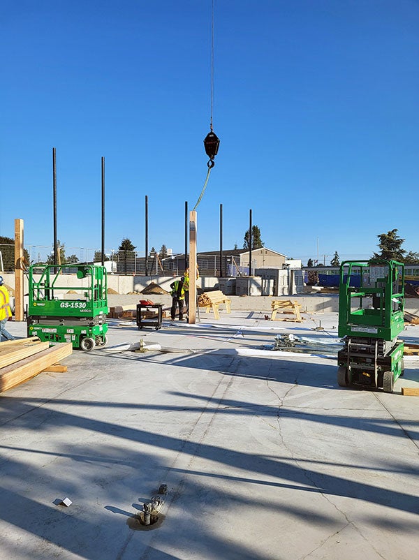 a glulam column is being lifted into place by a crane