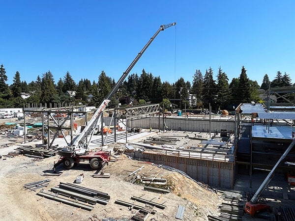 a crane is lifting steel beams over a concrete slab
