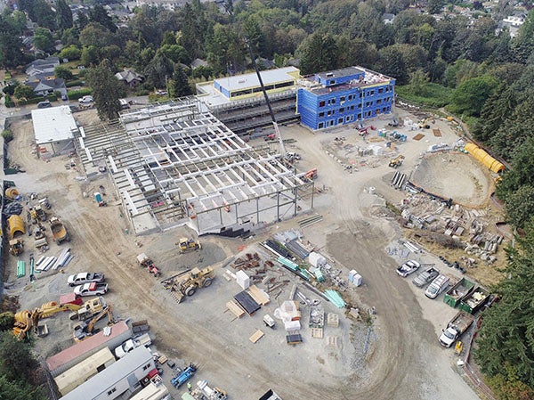 aerial view of a large construction site with part of the building showing walls and part still structural steel