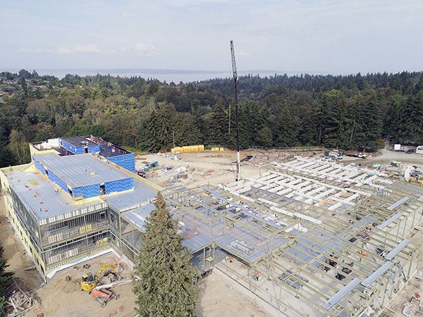 Aerial view of a large construction site surrounded by evergreen trees