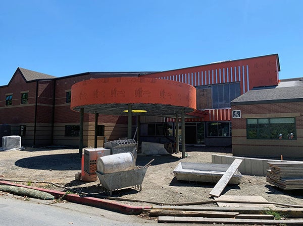 a round canopy on metal posts in front of a two story building under construction
