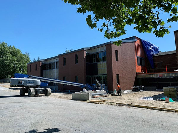 atwo-story building with brick on part of the walls and a construction lift