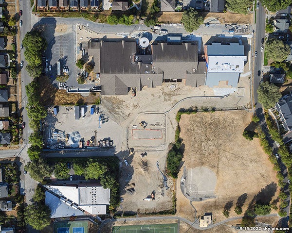 aerial view of a large building with bare dirt on the lower side of the photo