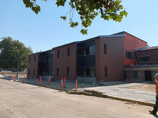 a brick and metal panel 2 story building with part of it still showing weather wrap material