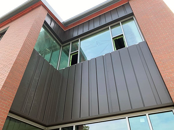 part of a brick building with metal panels above and below a corner window