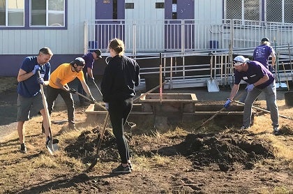 A group of volunteers work on the grounds on a school campus