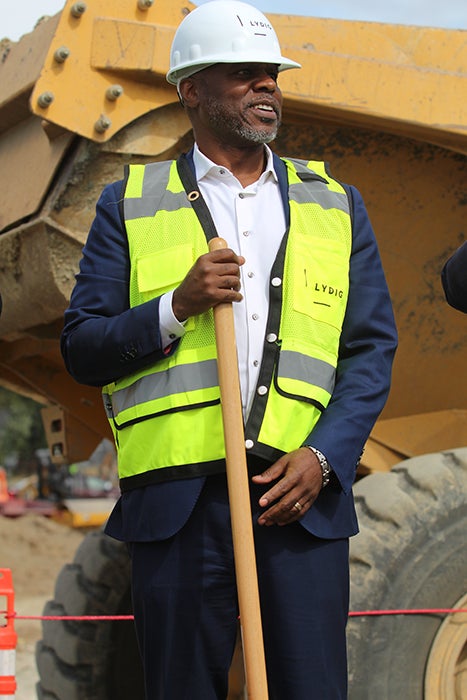 a man in a hard hat and yellow vest holds a shovel
