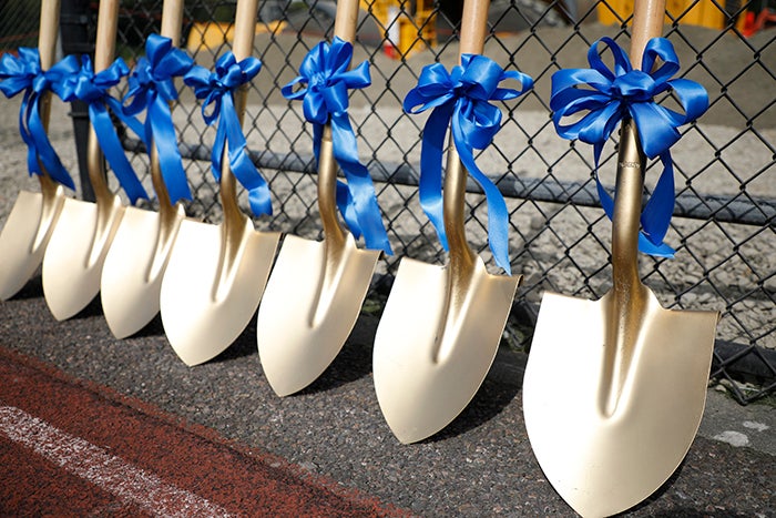gold shovels with blue bows leaning against a chain link fence