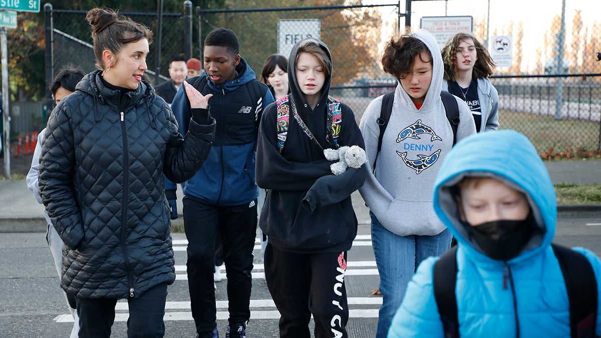 Students and adults walk together across a crosswalk