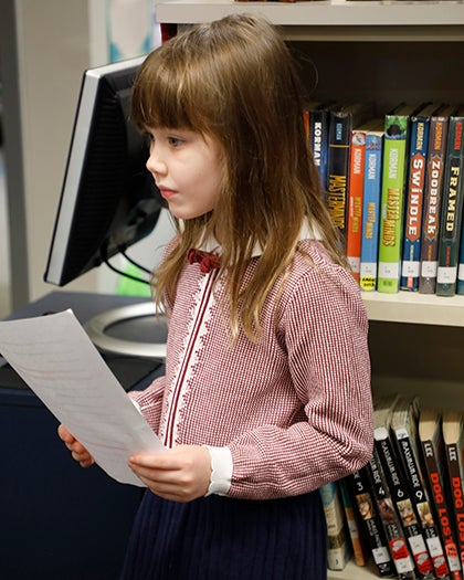 A student prepares for a classroom activity while holding a piece of paper