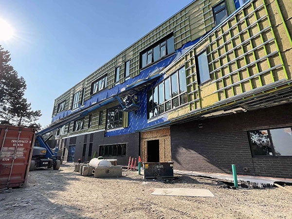 a three story building under construction with metal grid on side